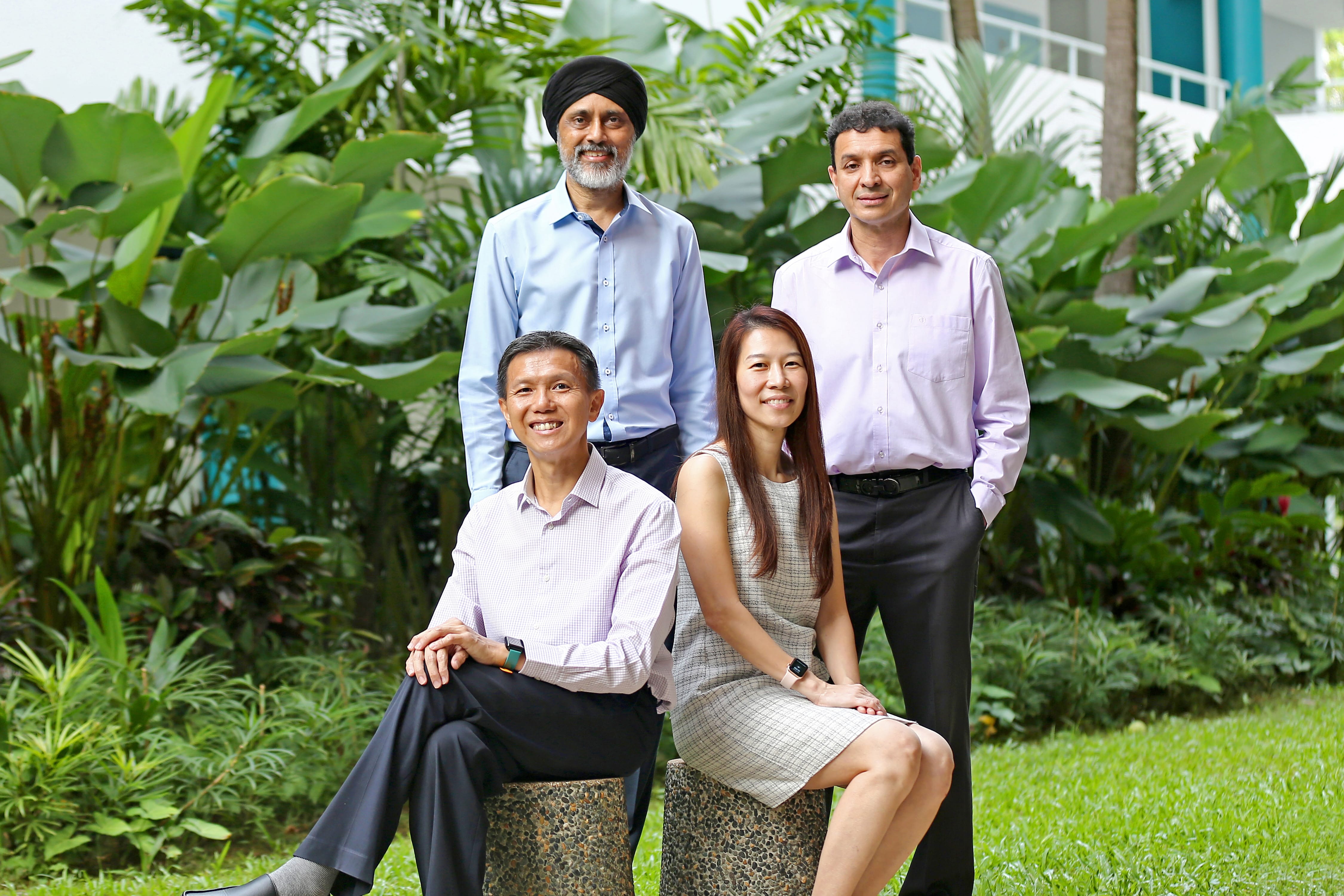Image of 2 men standing behind a seated man and woman